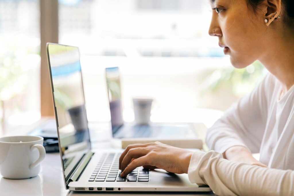 crop woman typing on laptop keyboard in cafe